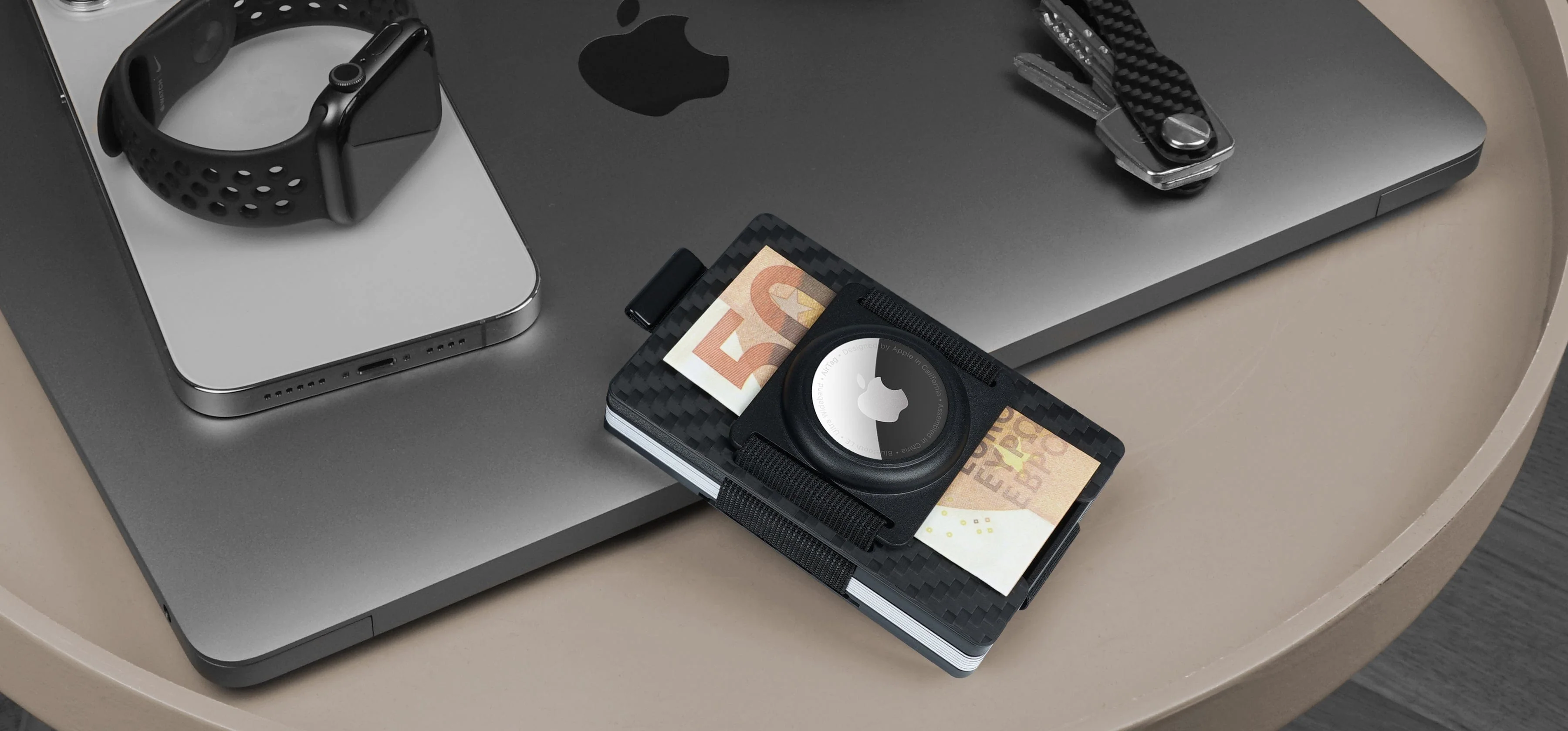 AirTag wallet setup on a desk with Apple devices, used as homepage hero image